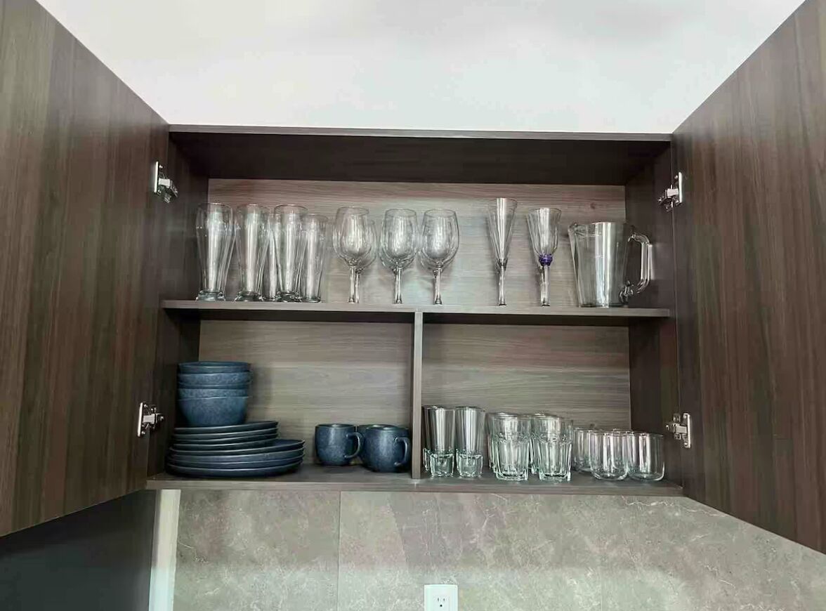 A kitchen cabinet with shelves holding various glassware and plates.