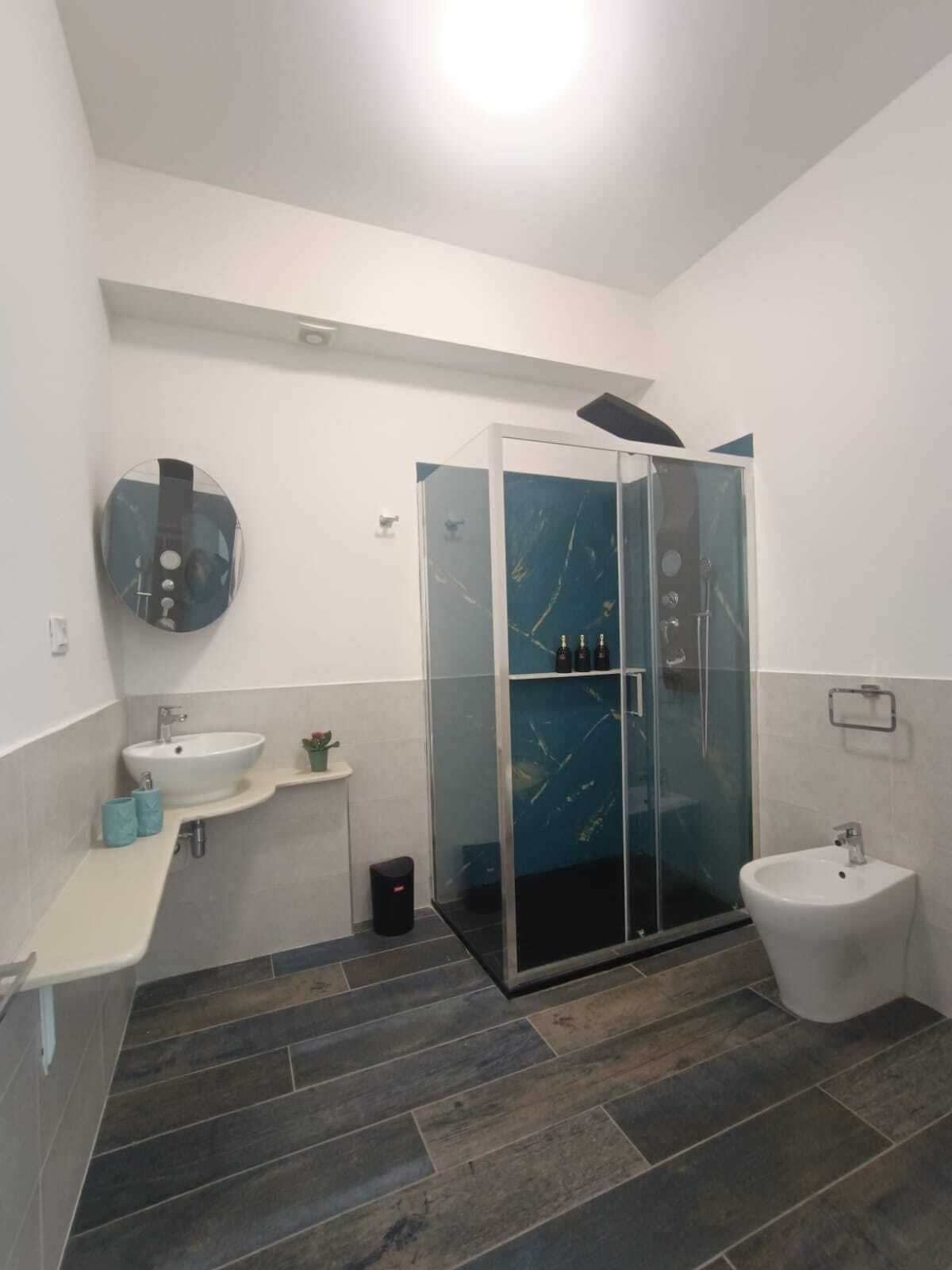 Ein modernes Badezimmer mit einer Duschkabine aus Glas, einem Waschbecken und einem Bidet.