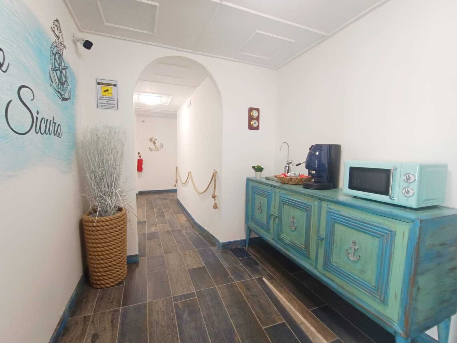 Un pasillo con un mueble azul turquesa, una planta pequeña y un letrero que dice 'Sicuro'.
