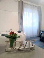 Una stanza con una grande finestra, una vasca da bagno e un cartello con la scritta 'LOVE'.
