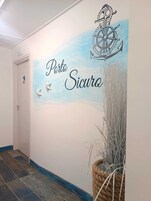 Un corridoio con un murale raffigurante un'ancora e il testo 'Porto Seguro'.