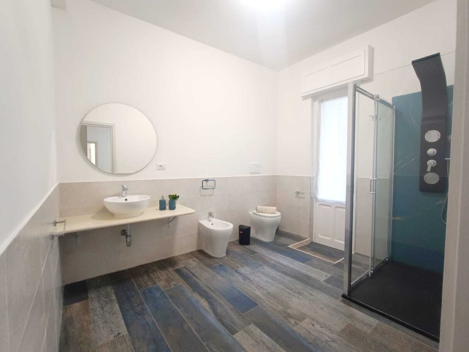 Un bagno moderno con un grande specchio, due lavabi, un bidet e una cabina doccia in vetro.