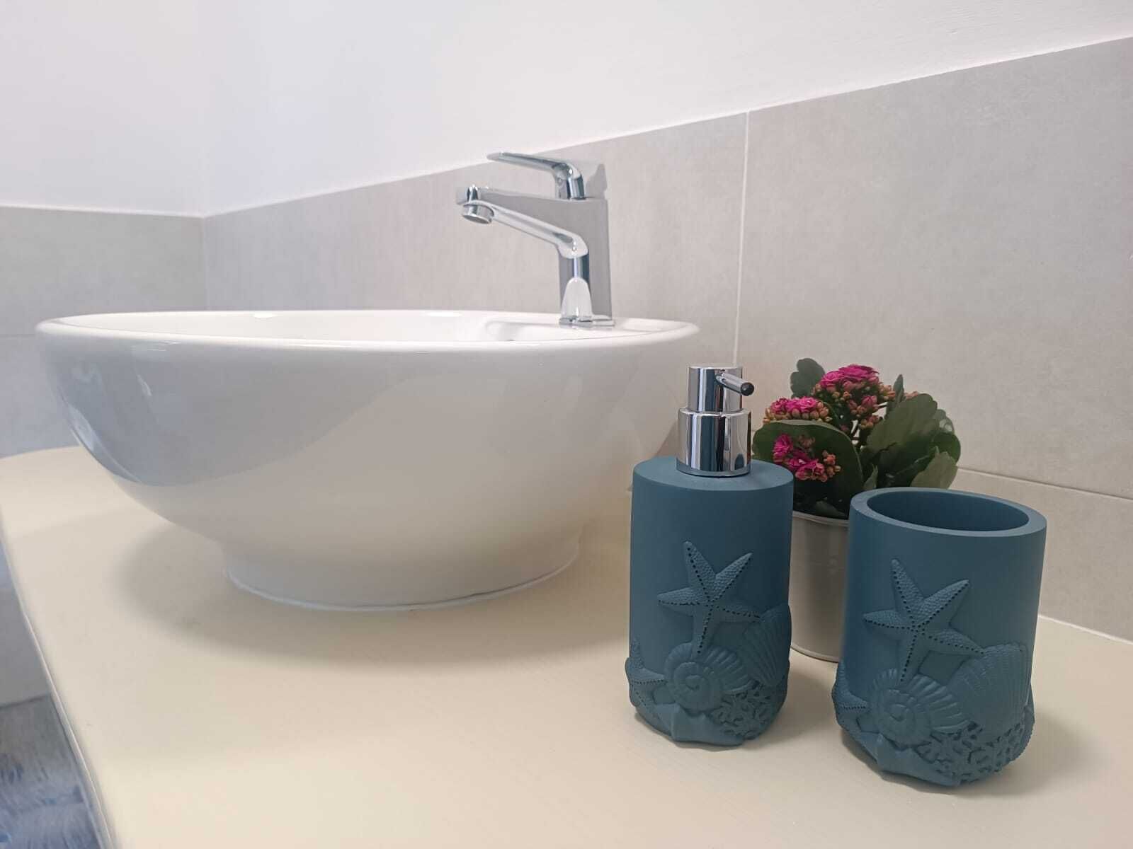 Un baño con un lavamanos blanco, un grifo y dos recipientes azules decorados con motivos de estrellas de mar.