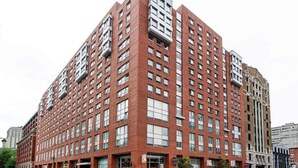 Un immeuble à plusieurs étages, doté d’une façade en briques rouges, de grandes fenêtres et de balcons.