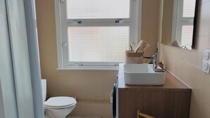 A bathroom with a toilet, sink, and window.