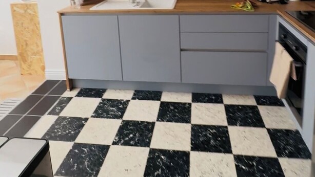 A modern kitchen with a checkered floor, grey cabinets, a wooden countertop, and a built-in microwave.