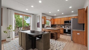 Una cocina moderna con armarios de madera, una isla central y una zona de comedor con mesa y sillas.