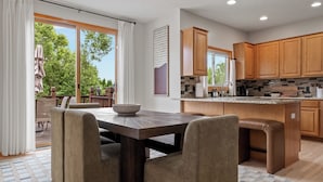Una cocina moderna con armarios de madera, una isla central y un comedor con mesa y sillas.