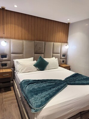 Una camera da letto moderna con un letto grande, una testiera in legno, lampade sui comodini e un pavimento in legno.