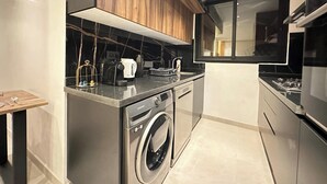 A compact kitchen with a washing machine, a coffee maker, and a microwave. - Beautiful 2-bedroom apartment in the heart of Gueliz (Marrakech)