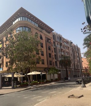 A multi-story hotel with a modern design, featuring balconies, large windows, and outdoor seating areas.