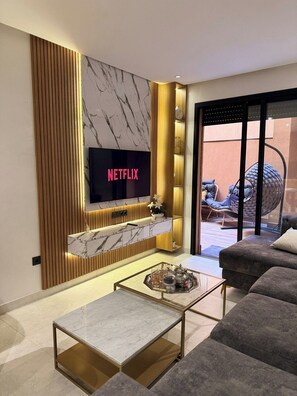 Una sala de estar moderna con un televisor de pantalla plana, una chimenea de mármol y una mesa de centro de vidrio.
