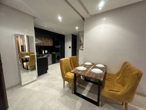 A modern kitchen with a dining area, featuring a central island, built-in oven, and a washing machine. - Charming 2-bedroom apartment in the heart of Gueliz (Marrakech)