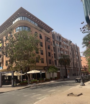 A multi-story hotel with a modern design, featuring balconies, large windows, and outdoor seating areas.