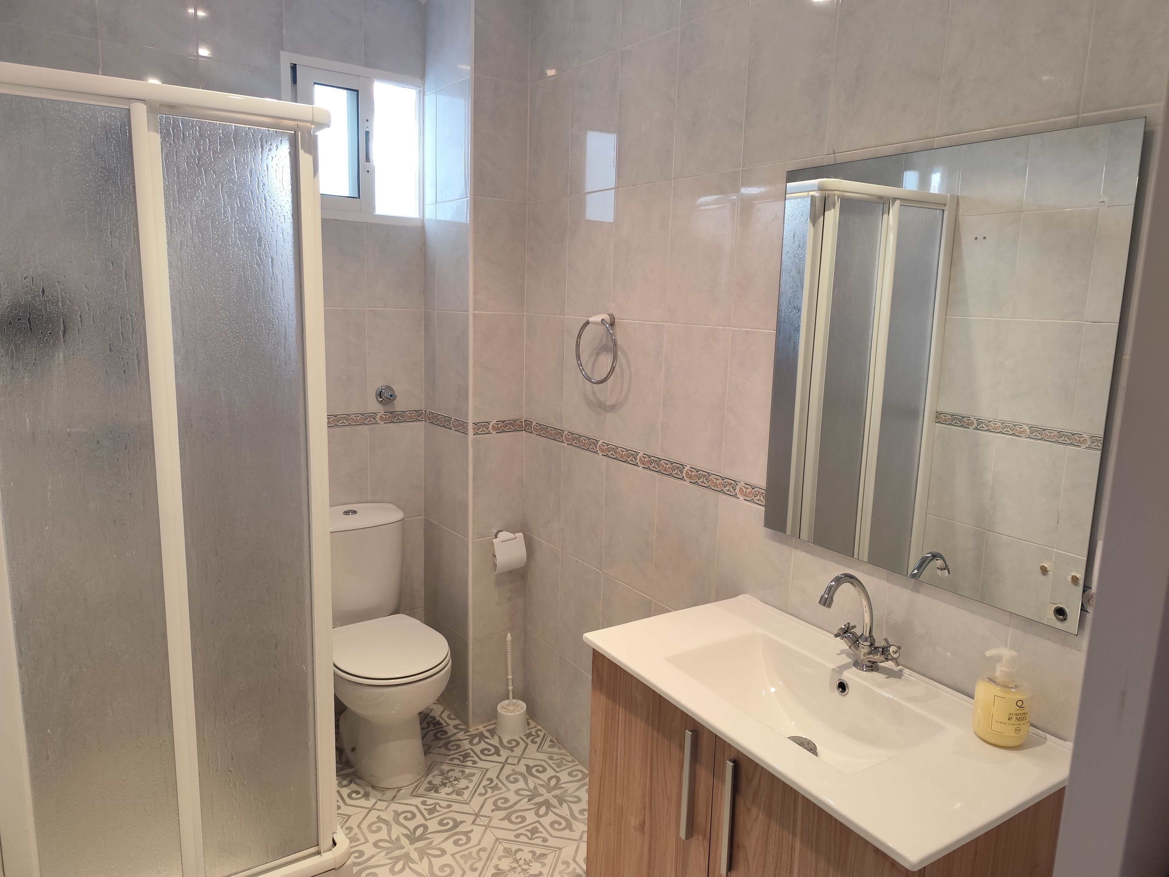 Een moderne badkamer met douche, toilet, wastafel en spiegel.