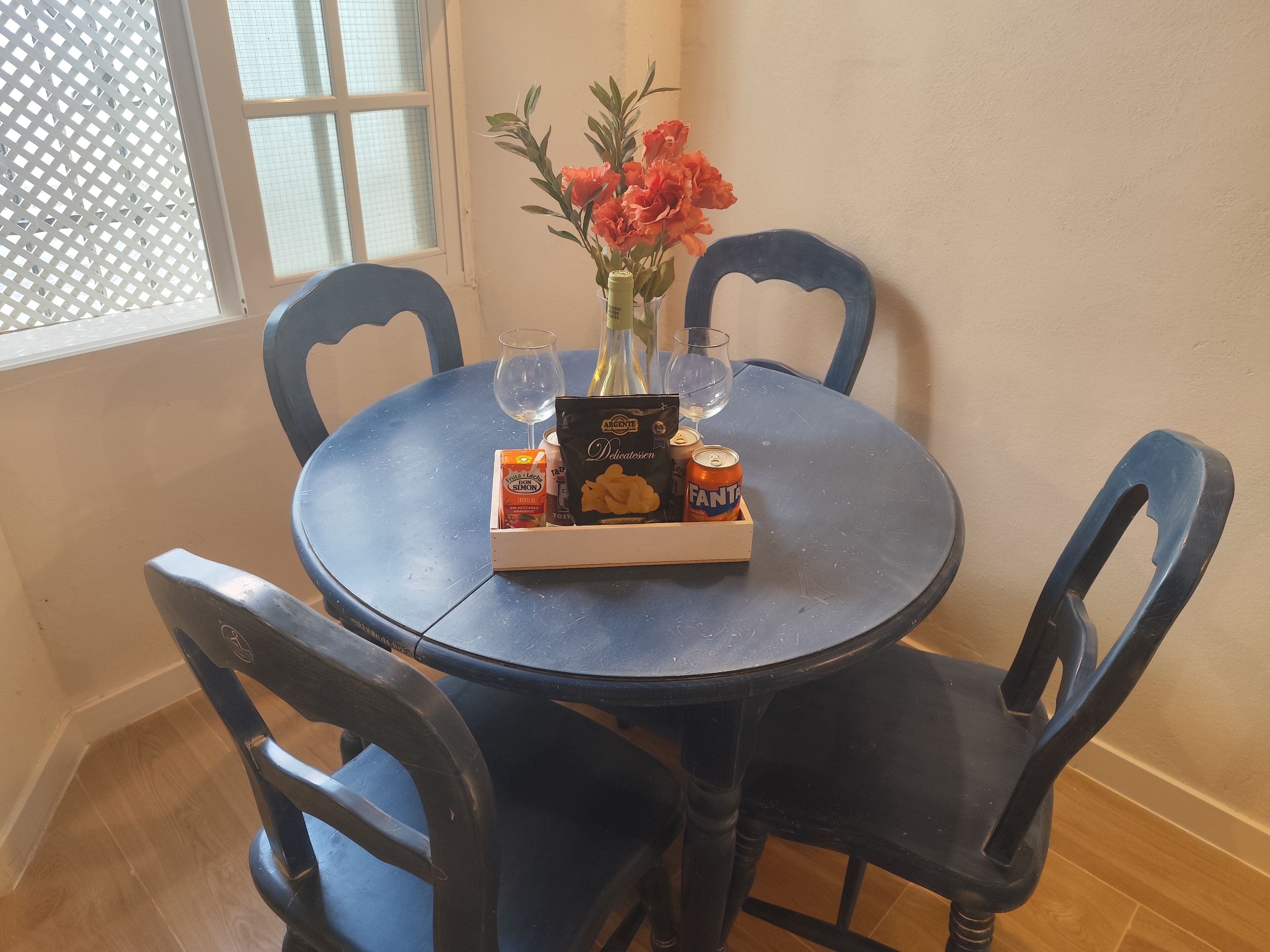 Een ronde tafel met een dienblad vol lekkernijen, een fles en twee glaasjes.