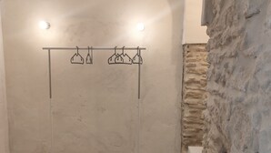 Un baño con ducha colgante, pared de piedra y baldosas de suelo con diseño.