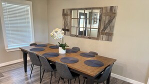 A dining area with a wooden table, six chairs, and a potted plant. - Charming 3-bedroom house with fitness room and AC in Bandera (Bandera)