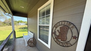 A porch with a white bench and a decorative sign. - Charming 3-bedroom house with fitness room and AC in Bandera (Bandera)