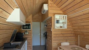 A compact, wood-paneled room with a kitchenette, a dining area, and a bookshelf.