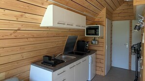 A compact kitchen with wooden paneling, a microwave, a coffee maker, and a sink.
