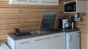 A compact kitchen with white cabinets, a built-in microwave, a coffee machine, and a sink. - La Cabane d'Antoine - MONT LOZERE ET GOULET (MONT LOZERE ET GOULET)