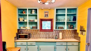 A kitchen with teal cabinets, a microwave, and a sink.