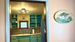A kitchen with green cabinets, a tiled backsplash, and a window above the sink.