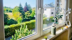 A window with a view of a garden and a house. - Chic Urban Stay 2BR with parking (Luxembourg City)