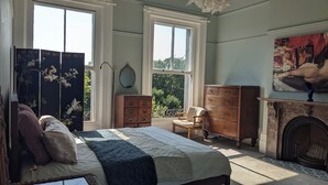 A bedroom with a large bed, a dresser, a chair, a fireplace, and a painting on the wall. - Huge 1 bed in Historical Garrison with Dover Castle View & Sea view. (Dover)