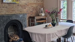A dining area with a brick wall, a fireplace, a table with chairs, and a hanging light fixture. - Huge 1 bed in Historical Garrison with Dover Castle View & Sea view. (Dover)