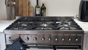 A kitchen with a stainless steel stove, oven, and a range hood. There are two bottles of olive oil on the counter. - Huge 1 bed in Historical Garrison with Dover Castle View & Sea view. (Dover)