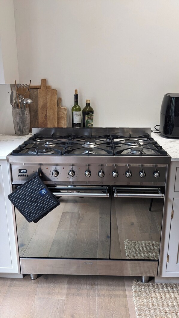 A kitchen with a stainless steel stove, oven, and a range hood. There are two bottles of olive oil on the counter. - Huge 1 bed in Historical Garrison with Dover Castle View & Sea view. (Dover)