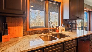 A kitchen with a granite countertop, stainless steel sink, and wooden cabinets.