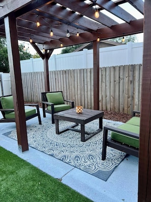 An outdoor patio with a wooden pergola, a table with chairs, and a decorative rug. - Pet friendly 3 Bedroom POOL Home in the Heart of Orlando (Orlando)