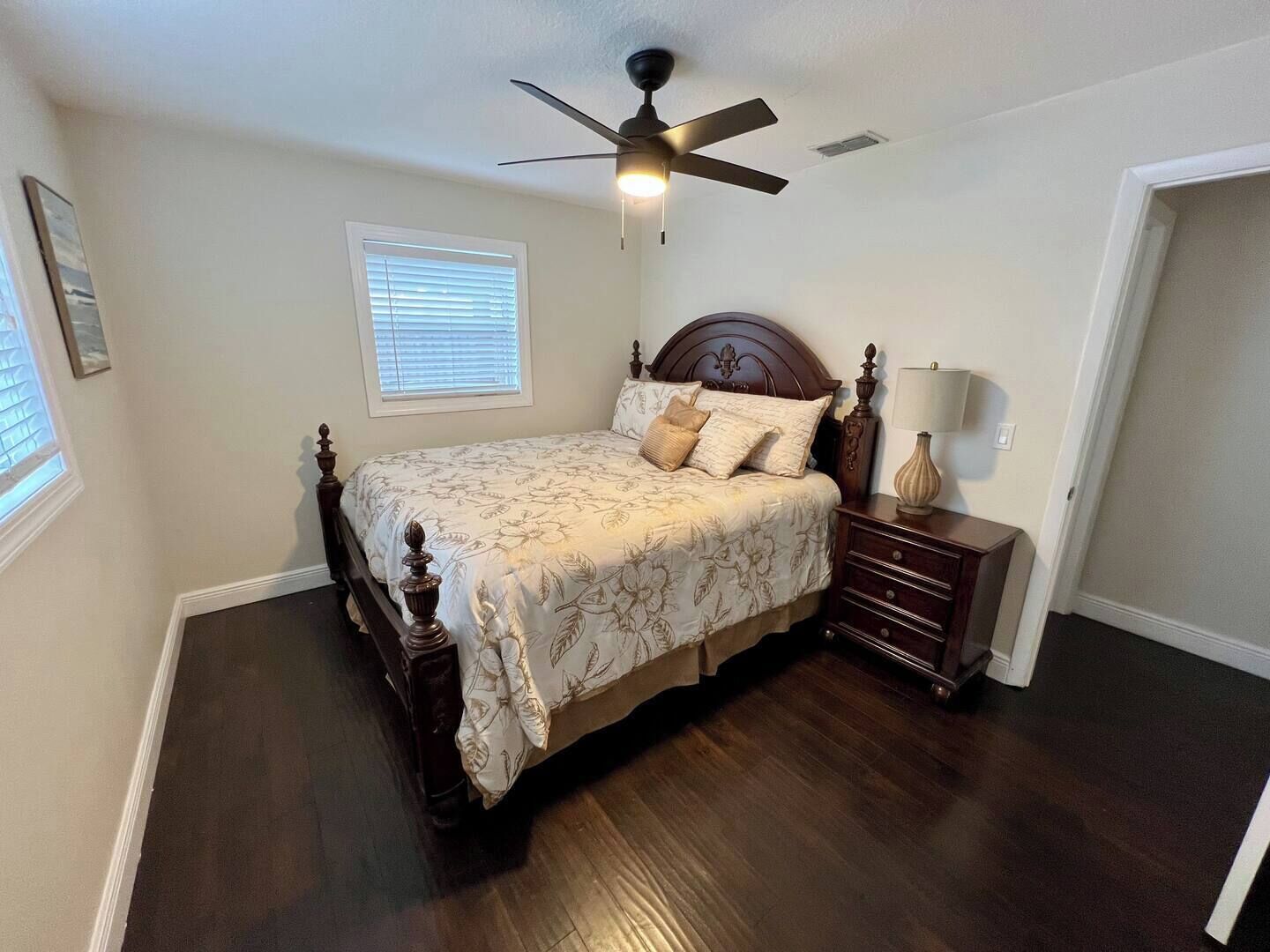 Une chambre à coucher avec un grand lit, un ventilateur de plafond, une table de chevet et une lampe.