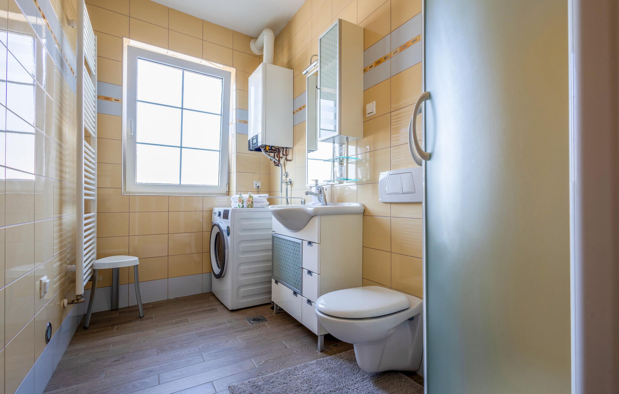 A compact bathroom with a washing machine, a sink, and a toilet.