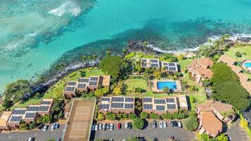 An aerial view of a resort with multiple buildings, a swimming pool, and a tennis court.
