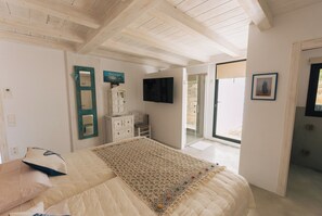 A bedroom with a bed, a TV, a dresser, and a door leading to an outdoor area. - Villa El Desbarbado (Montefrío)