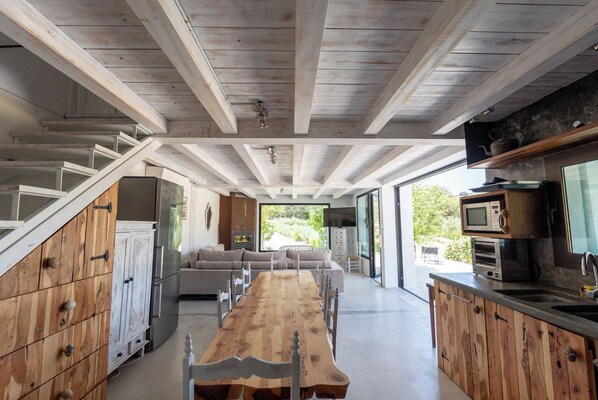 A modern kitchen with wooden cabinets, a long dining table, and built-in appliances. - Villa El Desbarbado (Montefrío)