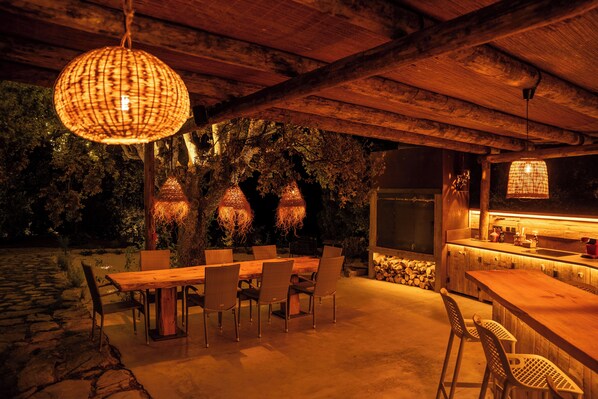 An outdoor dining area with a wooden table and chairs, surrounded by a stone wall and trees. - Villa El Desbarbado (Montefrío)