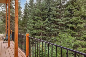 A wooden deck with a railing, overlooking a dense forest. - Private Hot Spring | River | Brundage | Off Grid (New Meadows)