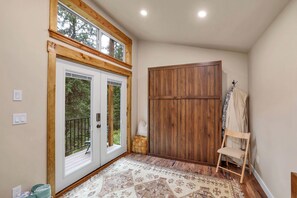 A room with a wooden door, a large window, and a wooden wardrobe. - Private Hot Spring | River | Brundage | Off Grid (New Meadows)