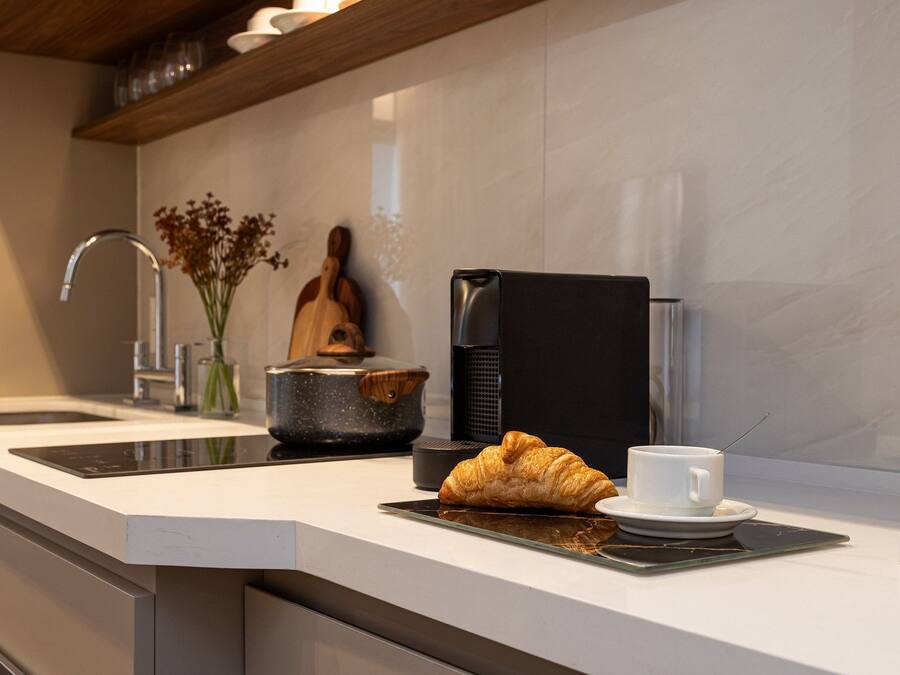 A modern kitchen with a coffee maker, a croissant, and a cup on the counter.