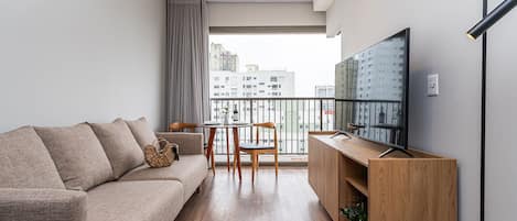 A modern living room with a sofa, TV, wooden cabinet, and a balcony with a city view.