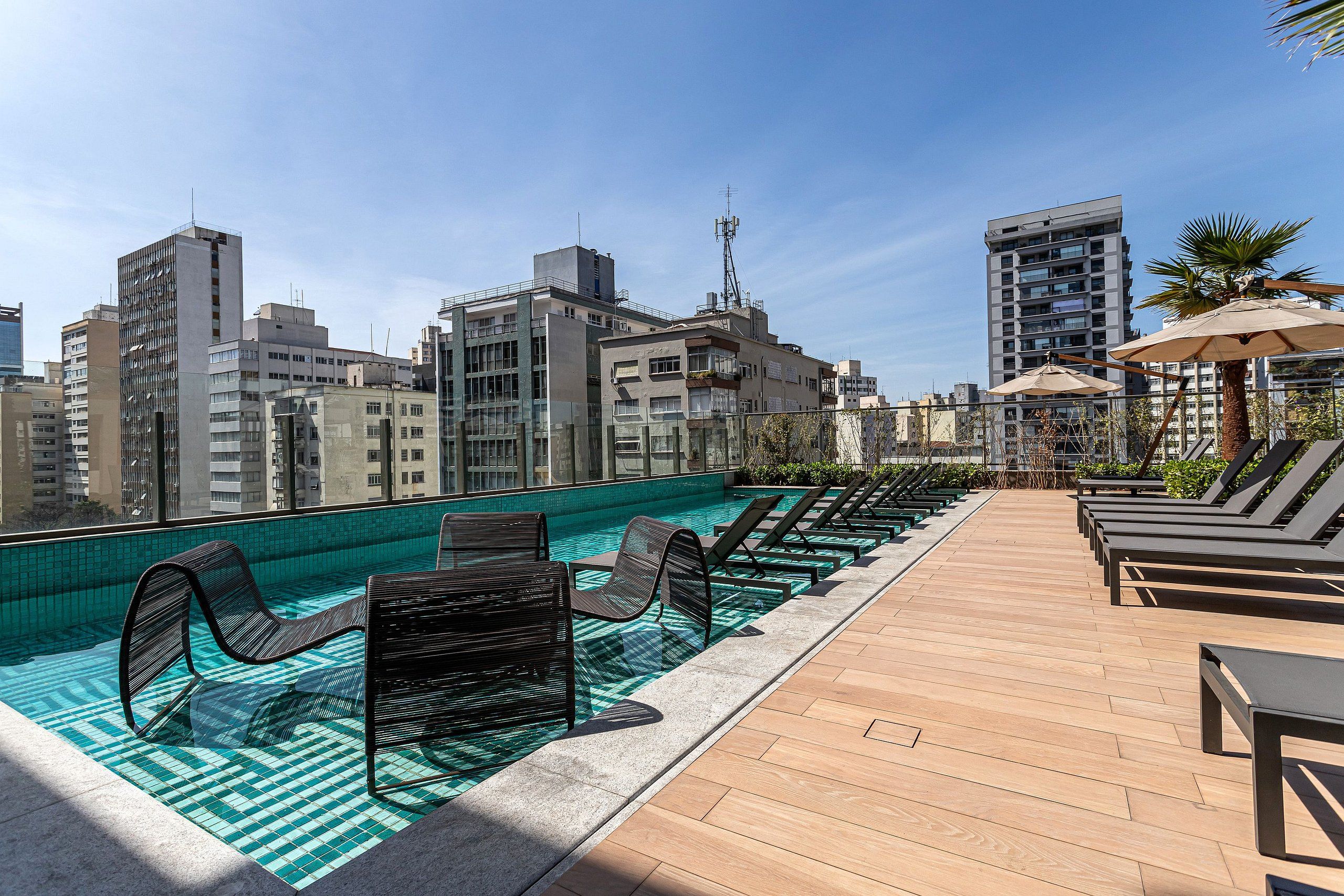 A rooftop pool area with lounge chairs and a wooden deck.