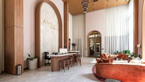 A modern hotel lobby with a bar, seating area, and a marble wall with the name 'AYRA'.