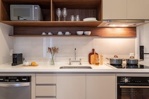 Une cuisine moderne équipée d’un four à micro-ondes, d’un four traditionnel et d’une cuisinière, ainsi que d’un évier et de divers ustensiles de cuisine.