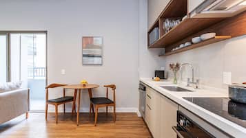 Cocina compacta con comedor, sillas de madera, una mesa redonda y vistas a través de un ventanal corredero.