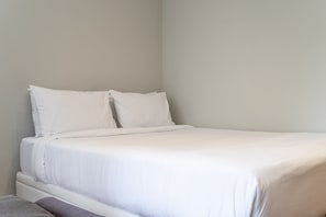 A single bed with white bedding in a room with plain walls. - Apartamentos mobiliados com excelente vista e localização - Higienópolis (São Paulo)